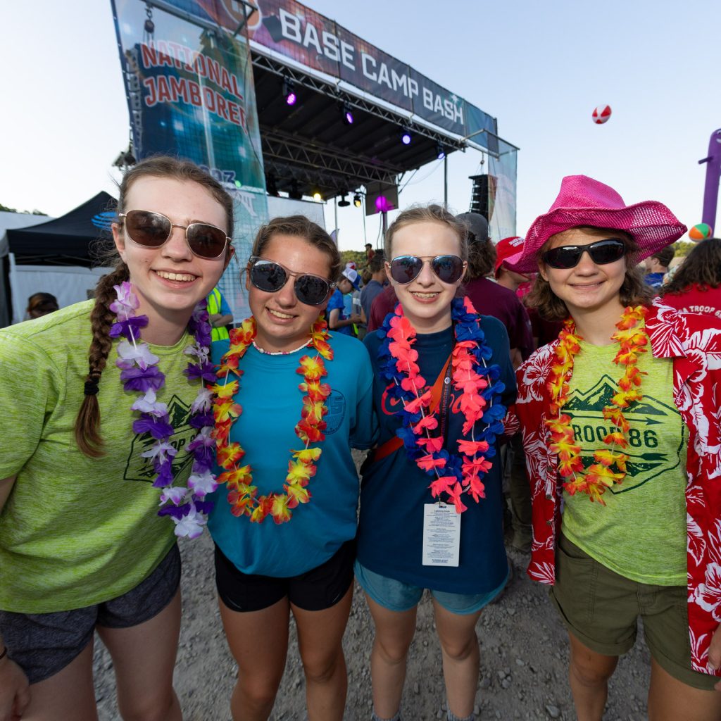 Scouts wearing flower leis and sunglasses at the base camp bash during the 2023 National Scout Jamboree at The Summit Bechtel Reserve in Mount Hope, West Virginia. (BSA Photo by Dan Glass)..**********Beginning of Shooting Data Section**********.20230722-19-35-25-80-DG     date - 7/22/23     time - 7:35:25 PM